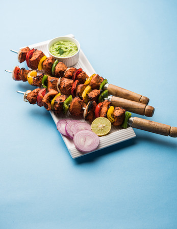 Chicken tikka /skew Kebab. Traditional Indian dish cooked on charcoal and flame, seasoned & colourfully garnished. served with green chutney and salad. selective focusの写真素材