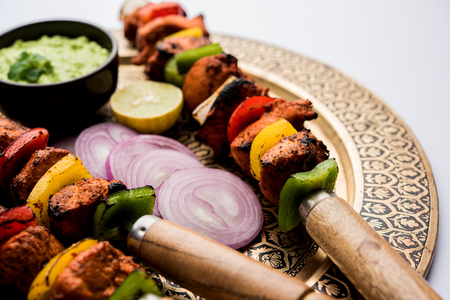 Chicken tikka /skew Kebab. Traditional Indian dish cooked on charcoal and flame, seasoned & colourfully garnished. served with green chutney and salad. selective focusの写真素材