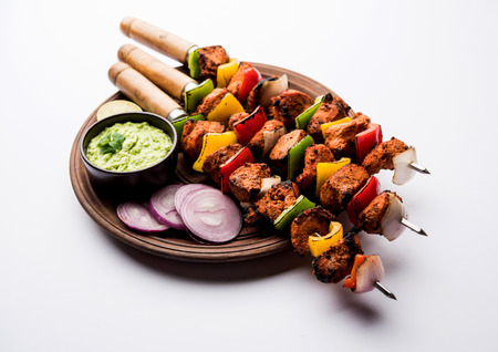 Chicken tikka /skew Kebab. Traditional Indian dish cooked on charcoal and flame, seasoned & colourfully garnished. served with green chutney and salad. selective focusの写真素材