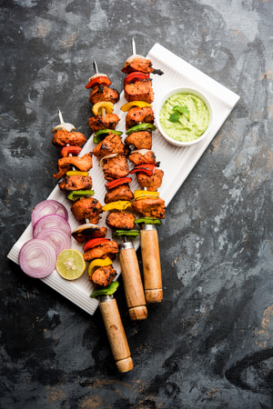 Chicken tikka /skew Kebab. Traditional Indian dish cooked on charcoal and flame, seasoned & colourfully garnished. served with green chutney and salad. selective focusの写真素材