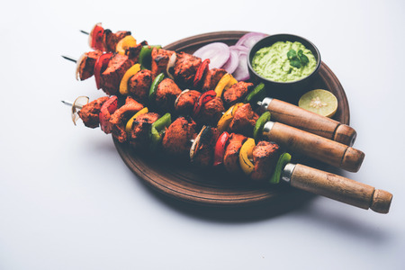 Chicken tikka /skew Kebab. Traditional Indian dish cooked on charcoal and flame, seasoned & colourfully garnished. served with green chutney and salad. selective focusの写真素材
