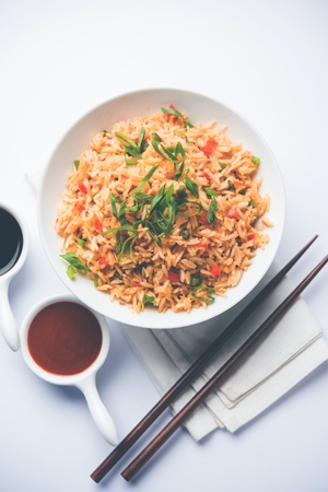 Schezwan Fried Rice Masala is a popular indo-chinese food served in a plate or bowl with chopsticks. selective focusの写真素材