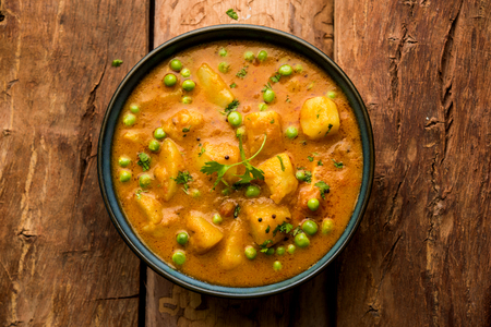 Indian Aloo Mutter curry - Potato and Peas immersed in an Onion Tomato Gravy and garnished with coriander leaves. Served in a Karahi/kadhai or pan or bowl. selective focusの写真素材