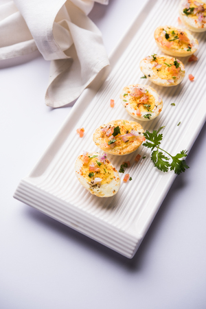 Fried hot boiled egg masala is a popular healthy breakfast or starter menu from India. With onion, coriander, black pepper, tomato and salt sprinkled over half of eggsの写真素材