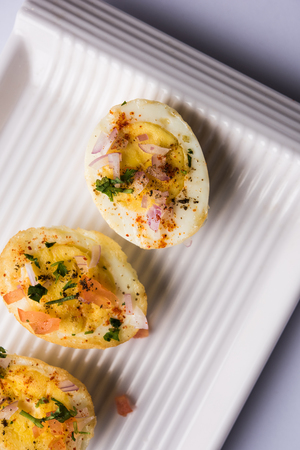 Fried hot boiled egg masala is a popular healthy breakfast or starter menu from India. With onion, coriander, black pepper, tomato and salt sprinkled over half of eggsの写真素材
