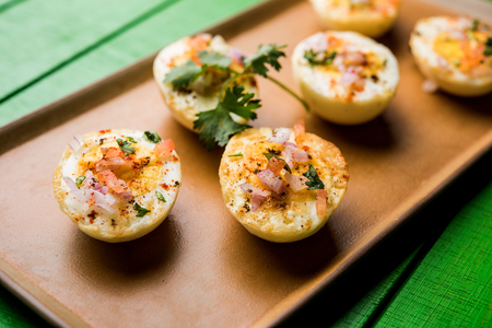 Fried hot boiled egg masala is a popular healthy breakfast or starter menu from India. With onion, coriander, black pepper, tomato and salt sprinkled over half of eggsの写真素材