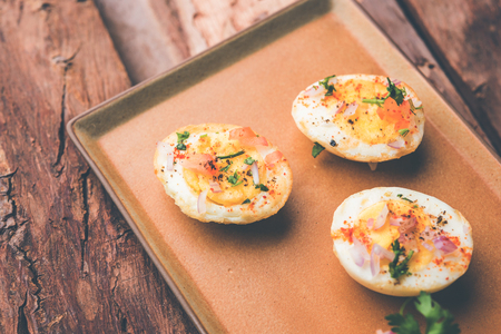 Fried hot boiled egg masala is a popular healthy breakfast or starter menu from India. With onion, coriander, black pepper, tomato and salt sprinkled over half of eggsの写真素材