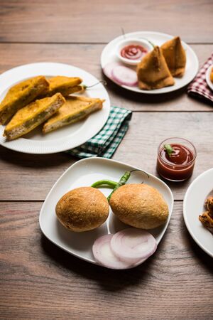Indian Tea time snacks  in group includes Veg Samosa, Kachori/kachaudi, aloo bonda, khaman dhokla, bread, onion,chilli and moong pakora/pakoda/bhaji/bhajji/Bhajiya/bajji with sauces, selective focusの写真素材
