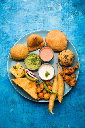 Indian Tea time snacks  in group includes Veg Samosa, Kachori/kachaudi, aloo bonda, khaman dhokla, bread, onion,chilli and moong pakora/pakoda/bhaji/bhajji/Bhajiya/bajji with sauces, selective focusの写真素材