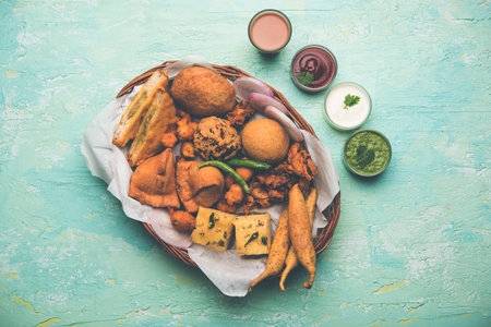 Indian Tea time snacks  in group includes Veg Samosa, Kachori/kachaudi, aloo bonda, khaman dhokla, bread, onion,chilli and moong pakora/pakoda/bhaji/bhajji/Bhajiya/bajji with sauces, selective focusの写真素材