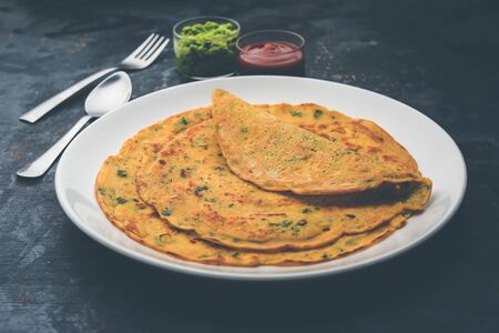 Chilla or Besan cheela is a simple pancake made with chickpea flour and some basic ingredients served with green chutney and tomato sauce, also known as veg-omeletteの写真素材