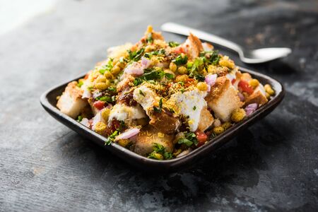Bread chaat/chat is a yummy starter/appetizer from India, served in a bowl garnished with tomato, sev and coriander and masala. selective focusの写真素材