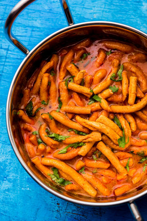 Dhaba style Sev bhaji/sabzi/curry made in tomato curry with gathiya shev, served in kerahi,...