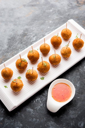 Crispy Veg lollipop recipe made using boiled potato with spices covered with corn flour and bread crumbs coating and then deep fried, served with toothpick or ice cream stock inserted in it with sauceの写真素材