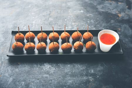 Crispy Veg lollipop recipe made using boiled potato with spices covered with corn flour and bread crumbs coating and then deep fried, served with toothpick or ice cream stock inserted in it with sauceの写真素材