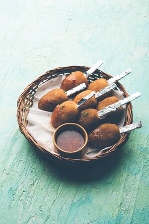 Crispy Veg lollipop recipe made using boiled potato with spices covered with corn flour and bread crumbs coating and then deep fried, served with toothpick or ice cream stock inserted in it with sauceの写真素材