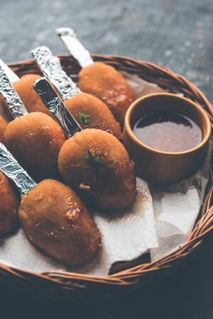 Crispy Veg lollipop recipe made using boiled potato with spices covered with corn flour and bread crumbs coating and then deep fried, served with toothpick or ice cream stock inserted in it with sauceの写真素材