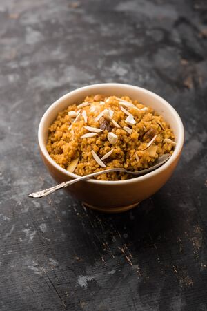 Wheat Laapsi/Lapsi/Shira/Halwa is an Indian sweet dish made of broken wheat or Daliya pieces and ghee along with nuts, raisins and dried fruits. It's a healthy food. served in a bowl, selective focusの写真素材