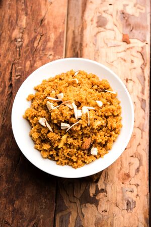 Wheat Laapsi/Lapsi/Shira/Halwa is an Indian sweet dish made of broken wheat or Daliya pieces and ghee along with nuts, raisins and dried fruits. It's a healthy food. served in a bowl, selective focusの写真素材