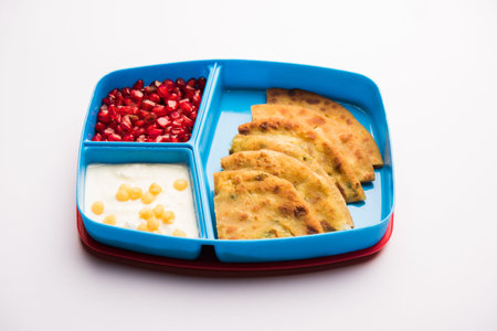 Lunch Box / Tiffin for Indian kids, includes Aloo Paratha, curd boondi and pomegranate seedsの写真素材