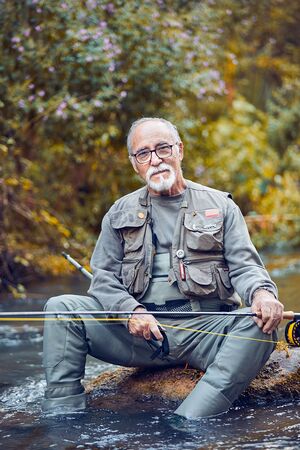 Senior man fishing in river sitting posing couple stillの写真素材