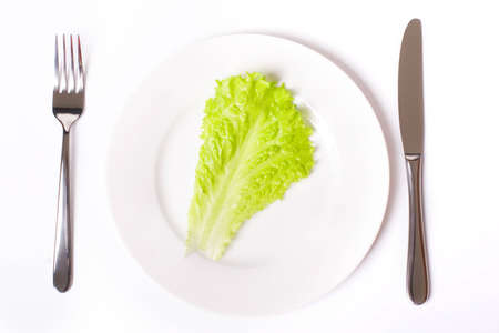 Green salad on white plate with knife and fork, with soft shadowの写真素材