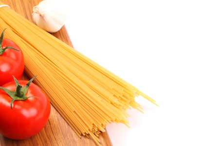 uncooked spaghetti and tomatos are located right on a white backgroundの写真素材