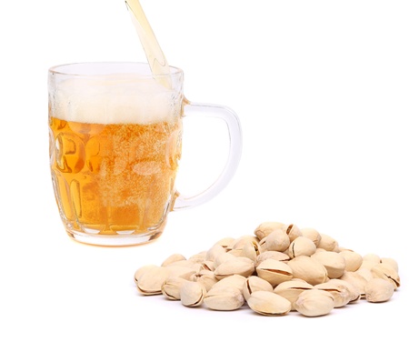 Glass of beer and pistachios on a white backgroundの写真素材
