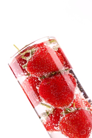 Strawberries and bubbles into glass on a white backgroundの写真素材