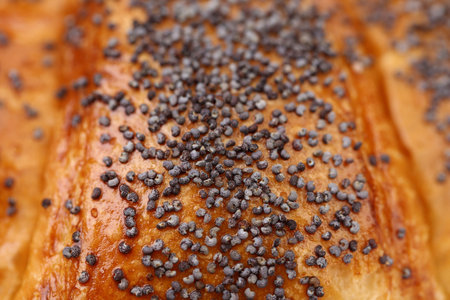 Close up fresh croissant with a poppy. Macro.