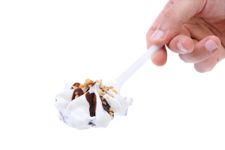 Hand holds ice cream on a spoon. White background.