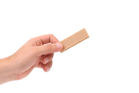 Hand holds wafer of chocolate. Isolated on a white background.の写真素材