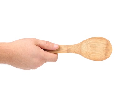 Hand holds wooden spoon. Isolated on a white backgroundの写真素材