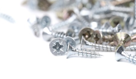 Zinked and anodized screws. Blurred. Isolated on a white background.の写真素材