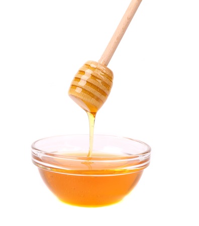 Honey flowing on spoon in a bowl. On a white.の写真素材
