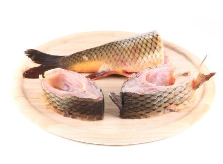 Fillets and tail raw carp on a wooden board. Isolated.
