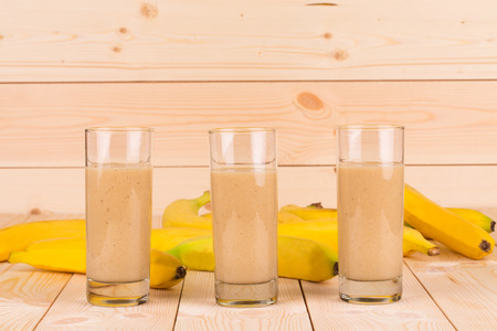 Close up of banana smoothie and fruits on wood.の写真素材