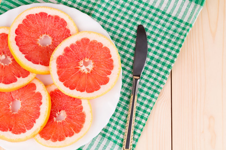 Composition of sliced grapefruit and knife on tablecloth.の写真素材