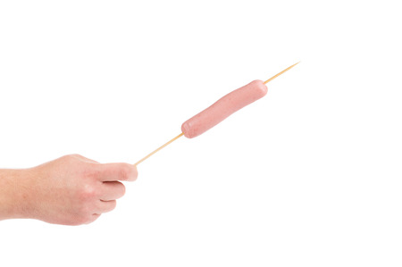 Hand holds sausage on stick isolated on a white backgroundの写真素材