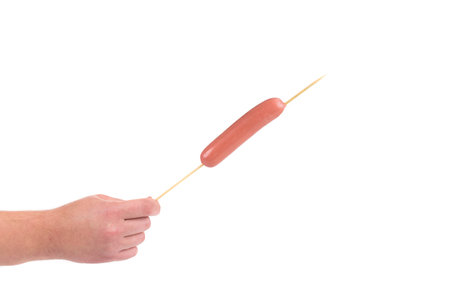 Hand holds sausage on stick isolated on a white backgroundの写真素材