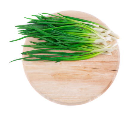 Bunch of green onion on wooden platter. Isolated on a white background.の写真素材
