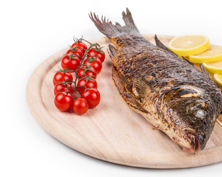 Grilled carp on platter with tomatoes. Isolated on a white background.