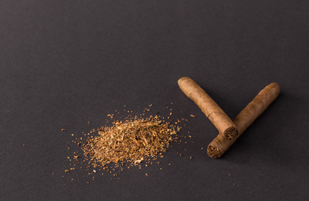 Cigars and heap of tobacco. Located on a black background.の写真素材
