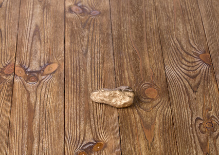 Shiny golden nugget locate on the brown wooden textureの写真素材