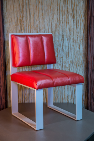Red leather chair with white legs situated on wallpaper backgroundの写真素材