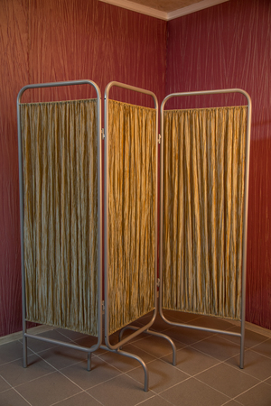 Folding screen standing in the corner of a room with red wallpapersの写真素材