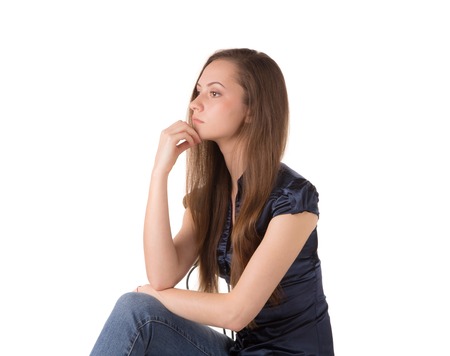 Portrait of beautiful young woman in blue blouse sitting on a chair and looking awayの写真素材