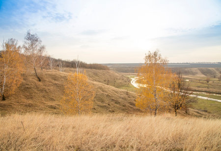 A small river flowing among hills and fields. An autumn landscape