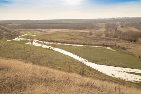 A small river flowing among hills and fields. An autumn landscape