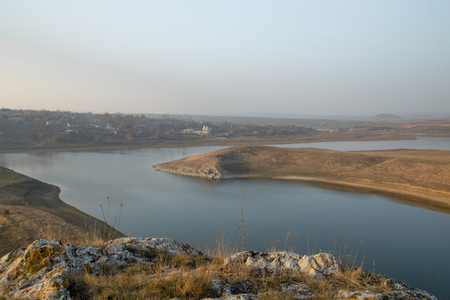 A panoramic view of beautiful river banks with grassy rocks and sky reflected in still watersの写真素材